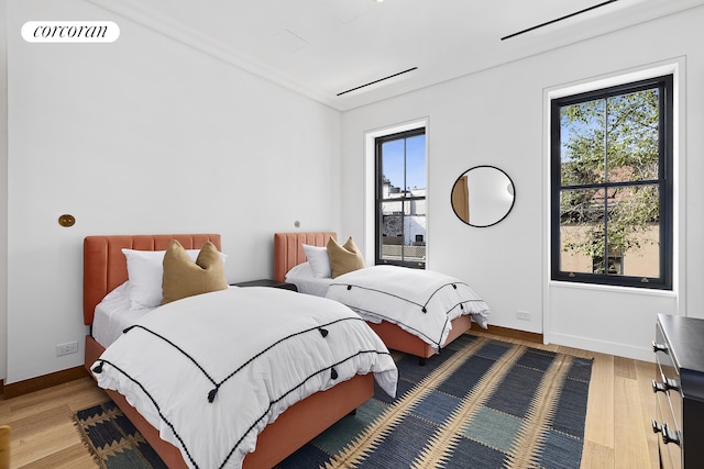 bedroom with visible vents, light wood-style flooring, baseboards, and multiple windows