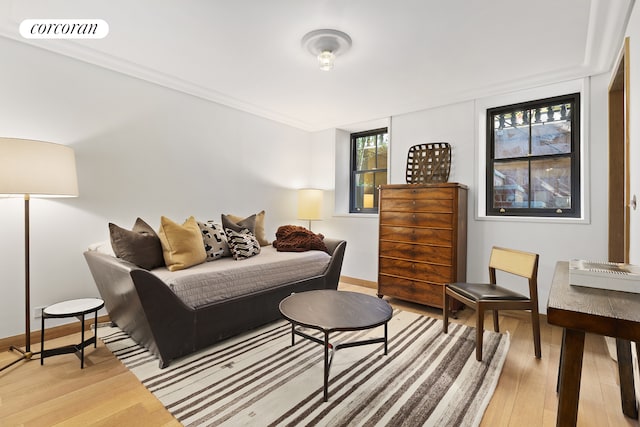 living room featuring crown molding, baseboards, visible vents, and light wood finished floors