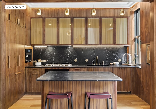 kitchen featuring dark countertops, a kitchen breakfast bar, tasteful backsplash, and a sink