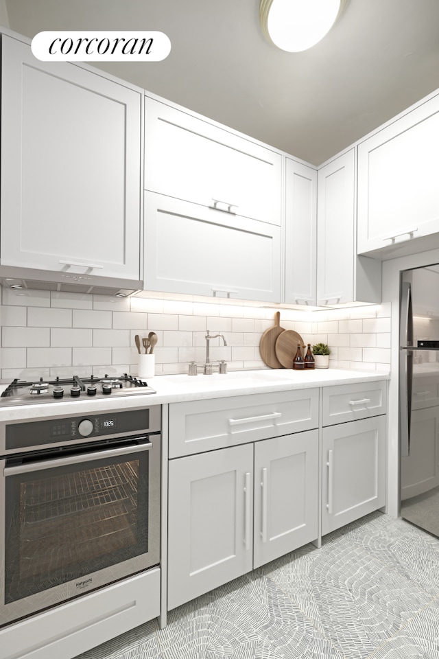 525 E 86th St Unit 3E, New York City, NY 10028 - kitchen with appliances with stainless steel finishes, backsplash, light countertops, a sink, and light tile patterned flooring