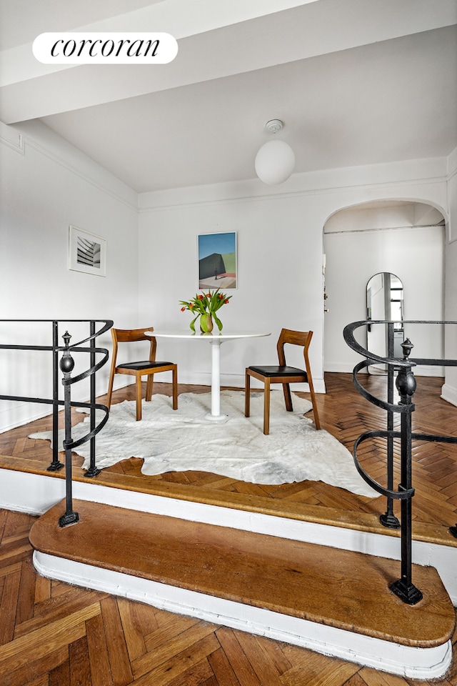 interior space featuring arched walkways, ornamental molding, wood finished floors, and baseboards