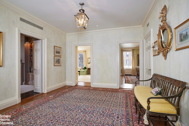 living area featuring baseboards, visible vents, wood finished floors, crown molding, and a chandelier