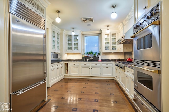 kitchen featuring dark wood-style flooring, a warming drawer, dark countertops, visible vents, and appliances with stainless steel finishes