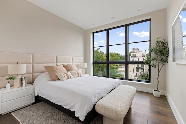 bedroom featuring dark wood-style floors, vaulted ceiling, and baseboards