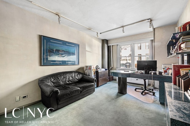 carpeted office featuring rail lighting and a textured ceiling