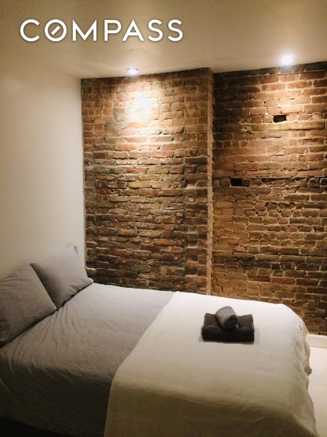 bedroom featuring brick wall