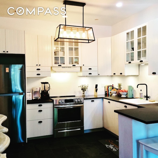 kitchen featuring dark countertops, under cabinet range hood, freestanding refrigerator, electric stove, and a sink