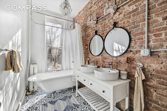 full bath featuring a freestanding bath, radiator, brick wall, and a sink