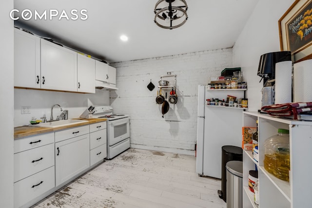 kitchen with white appliances, a sink, white cabinets, light wood-style floors, and under cabinet range hood