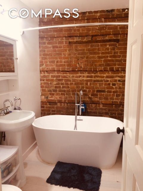 bathroom with brick wall and a freestanding bath