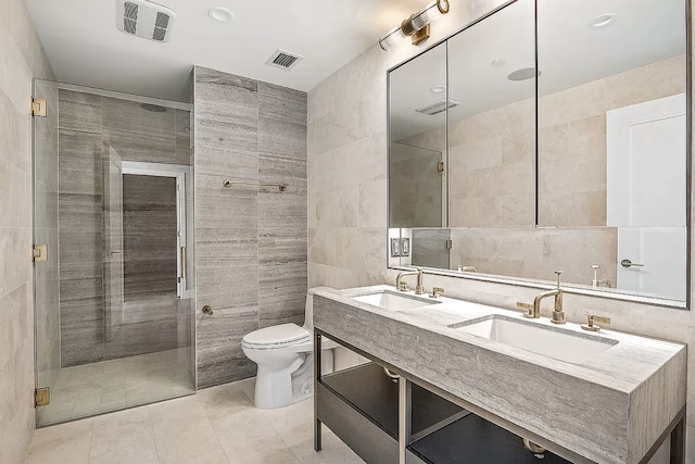 bathroom with visible vents, toilet, a sink, and tile walls