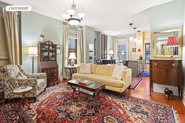 living area with wood-type flooring, baseboards, and a notable chandelier