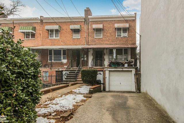 multi unit property featuring an attached garage, a porch, concrete driveway, and brick siding