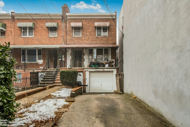 multi unit property with a garage, driveway, and brick siding