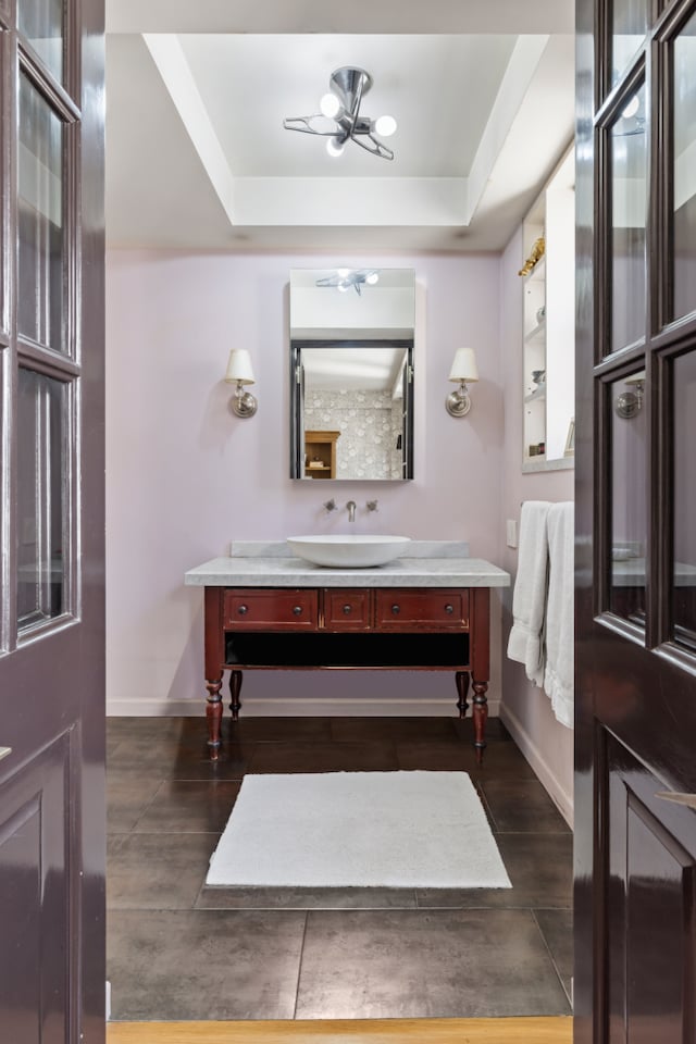 bathroom with baseboards, a tray ceiling, wood finished floors, and vanity