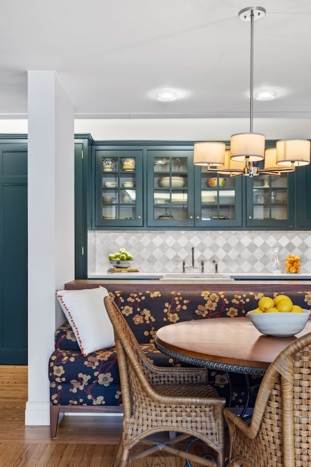 bar with a sink, backsplash, wood finished floors, and pendant lighting