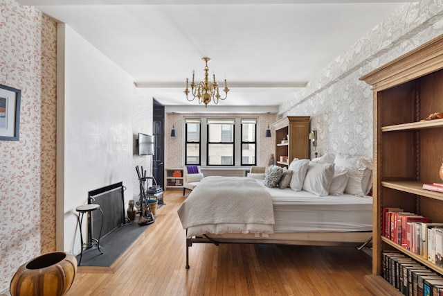 bedroom with wallpapered walls, wood-type flooring, and a chandelier