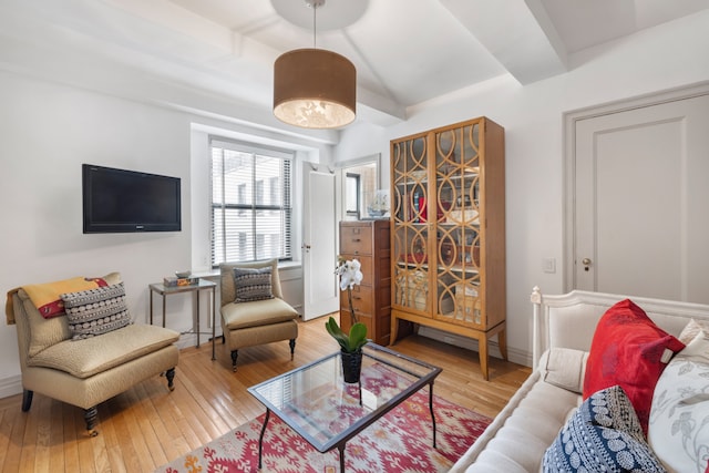 living area with baseboards, hardwood / wood-style floors, and beamed ceiling