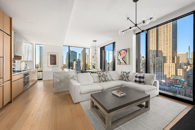 living room featuring light wood-type flooring, a city view, floor to ceiling windows, and an inviting chandelier