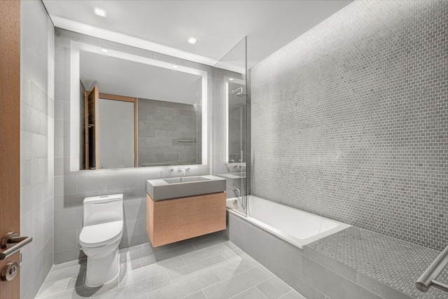 bathroom featuring tile walls, toilet, tiled shower / bath combo, vanity, and tile patterned flooring