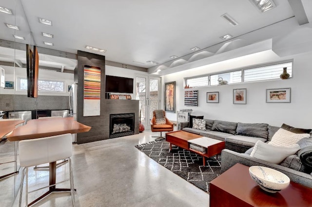 living room featuring concrete floors, a fireplace, and visible vents