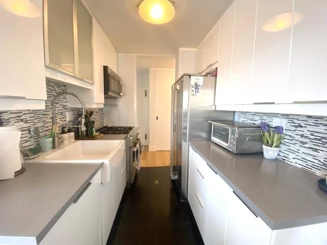 kitchen with white cabinetry, light countertops, backsplash, and appliances with stainless steel finishes