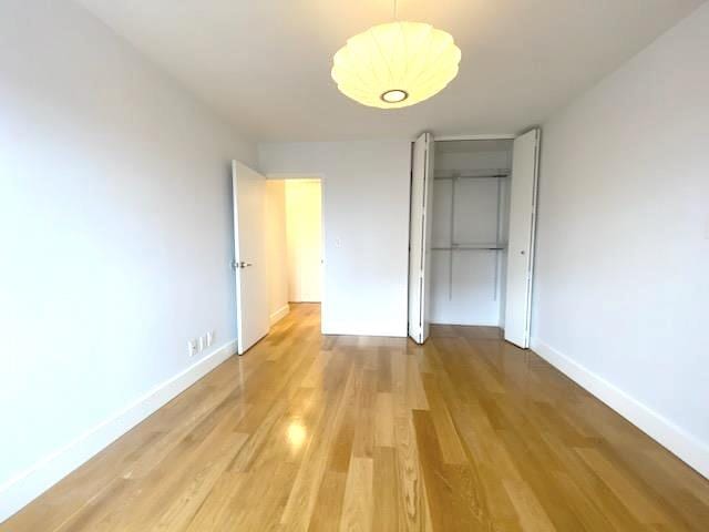 unfurnished bedroom featuring a closet, light wood-style flooring, and baseboards