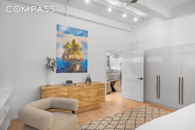 bedroom with light wood finished floors, rail lighting, and a towering ceiling