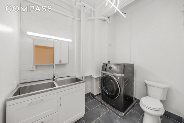 95 Vandam St Unit 2R, New York City, NY 10013 - washroom with washer / dryer and dark tile patterned floors