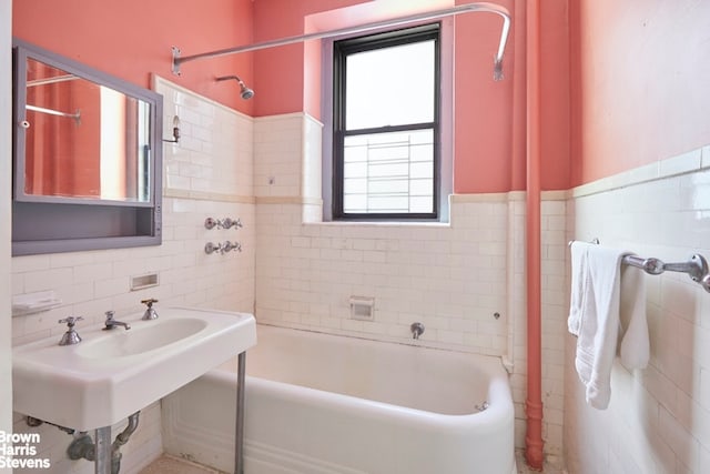 full bathroom with a tub to relax in, tile walls, a shower, wainscoting, and a sink