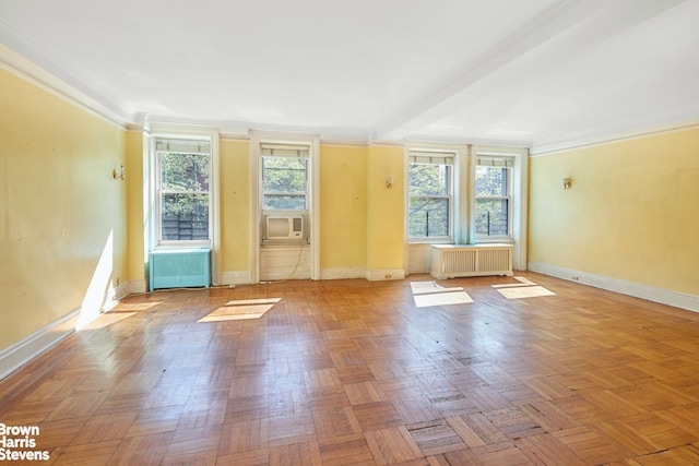 empty room featuring baseboards, crown molding, radiator heating unit, and a healthy amount of sunlight