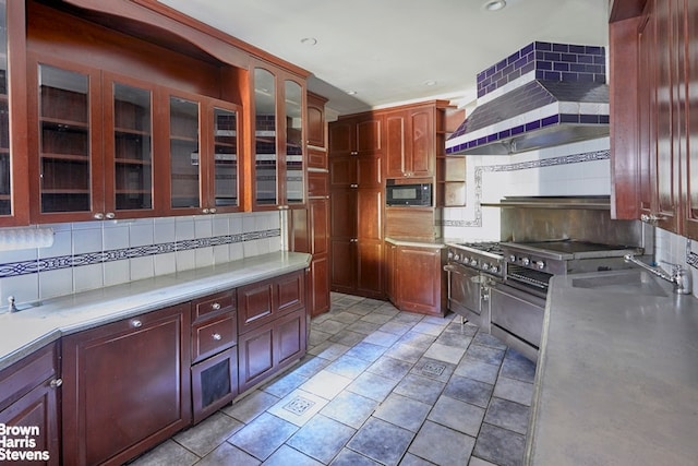 kitchen featuring wall chimney exhaust hood, a sink, light countertops, black microwave, and backsplash