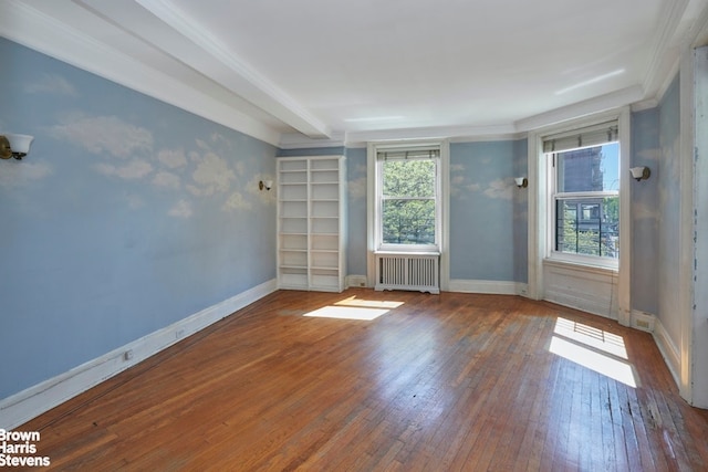 spare room featuring baseboards, wood-type flooring, and radiator