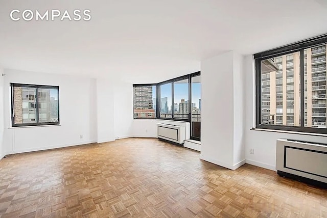 unfurnished room featuring a view of city and baseboards