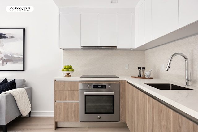 27-09 40th Ave Unit 3G, New York City, NY 11101 - kitchen featuring stainless steel oven, modern cabinets, light countertops, black electric cooktop, and backsplash