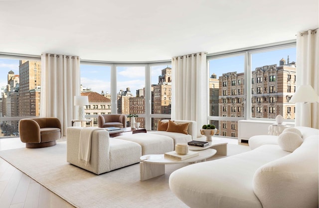 living area with floor to ceiling windows, a city view, and wood finished floors