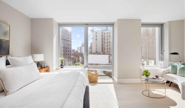 212 W 72nd St Unit 7J, New York City, NY 10023 - bedroom with wood finished floors, a view of city, and baseboards