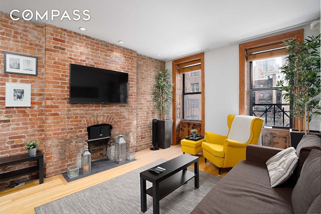 living area with brick wall, wood finished floors, and recessed lighting