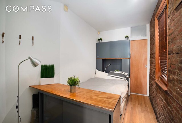 bedroom with brick wall and wood finished floors