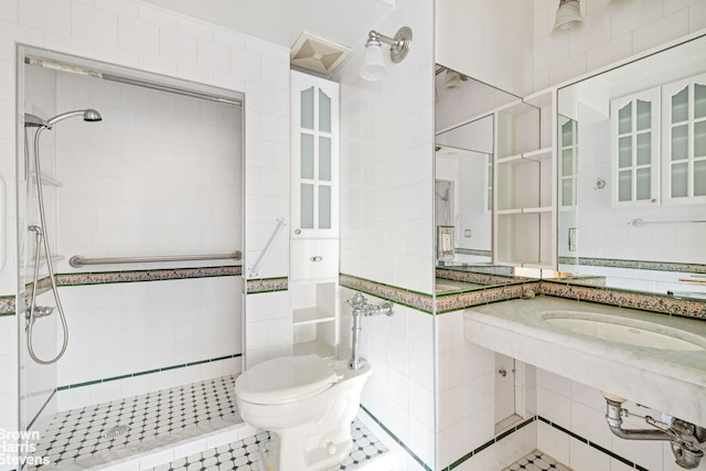 bathroom with tile walls, a sink, a shower stall, and toilet