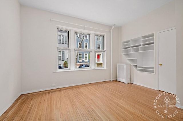 empty room with baseboards and wood-type flooring