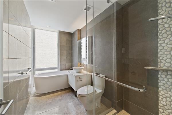 247 W 46th St Unit 1105, New York City, NY 10036 - full bath with tile walls, a soaking tub, vanity, a stall shower, and toilet