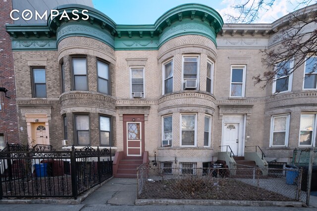 view of front facade featuring brick siding, cooling unit, entry steps, and a fenced front yard