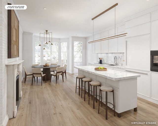 kitchen featuring tasteful backsplash, a sink, light wood-style flooring, and a center island