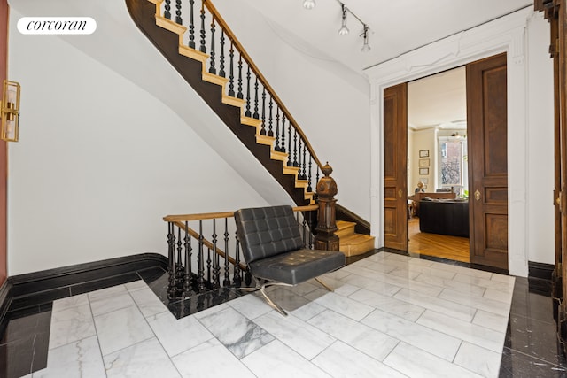 entryway with marble finish floor, baseboards, visible vents, and rail lighting