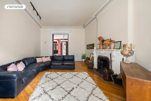 living room with crown molding, a fireplace, visible vents, and wood finished floors