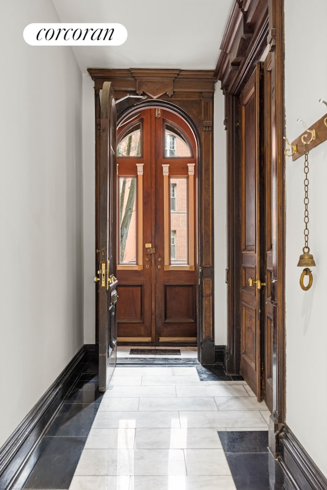 entrance foyer featuring baseboards, arched walkways, and french doors