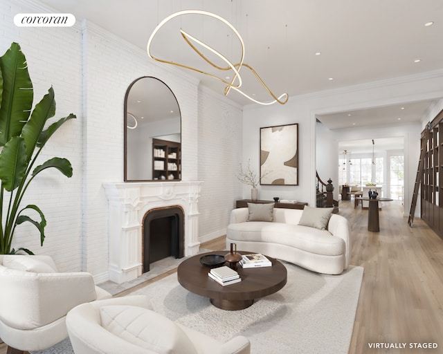 living area featuring light wood-style flooring, a notable chandelier, brick wall, a fireplace with flush hearth, and crown molding