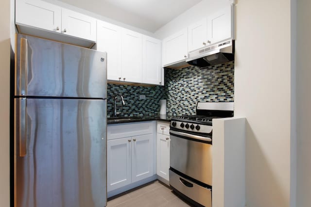 kitchen featuring backsplash, under cabinet range hood, white cabinets, stainless steel appliances, and a sink