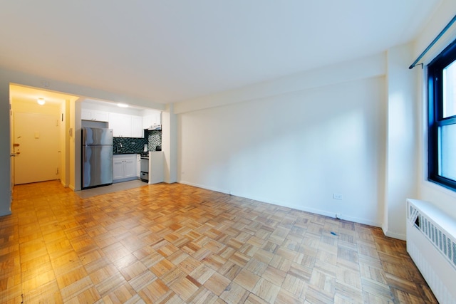 unfurnished living room featuring radiator heating unit and baseboards